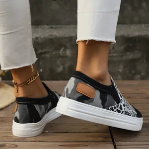 Close-up of women's camo and leopard print platform canvas loafers on a wooden floor