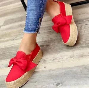Detailed view of women's red platform slip-on shoes featuring a large decorative bow