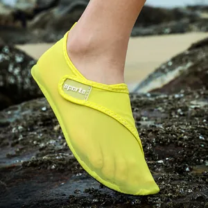 Detail view of breathable yellow mesh water shoe being worn on natural rocky beach terrain