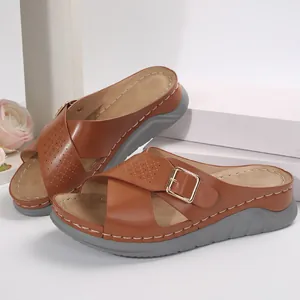 Perspective view of stylish brown wedge sandals with cross straps and buckle detail