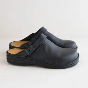 Side detail of men's matte black clogs with adjustable buckle strap and thick sole