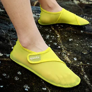 Close-up view of breathable yellow mesh water shoes being worn on a rocky outdoor beach surface