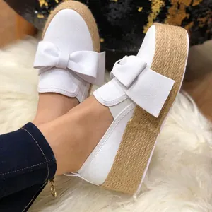 Stylish white platform espadrille shoes featuring a decorative large bow and jute rope sole