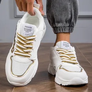 Macro view of white men's chunky sneakers featuring gold accents and thick woven laces