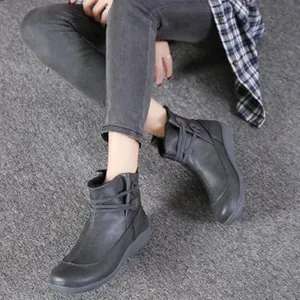 Detailansicht grauer Retro-Stiefeletten mit Kreuzgurt-Design auf weichem strukturiertem Leder