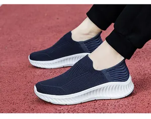 Detailed view of navy blue breathable knit slip-on sneakers on a red running track.