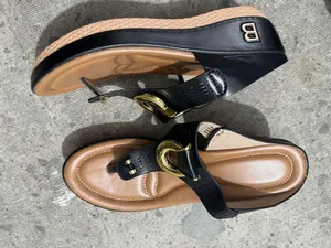 Close-up view of women's black wedge thong sandals with golden B-logo hardware detail