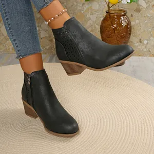 Close-up of black laser-cut Chelsea boots with chunky square heel and pointed toe