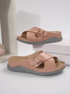 Macro view of women's pink platform sandals with cross straps and gold buckles.