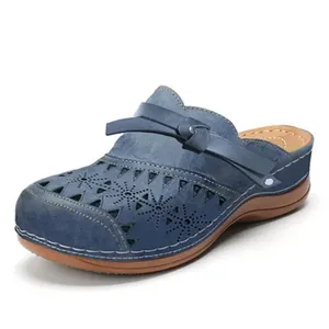 Detailed view of women's blue hollow-out wedge mules with laser-cut flower patterns