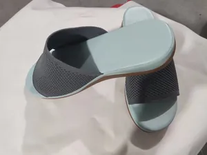 Detail view of casual flat slides with a grey knit upper and soft mint-colored footbed.