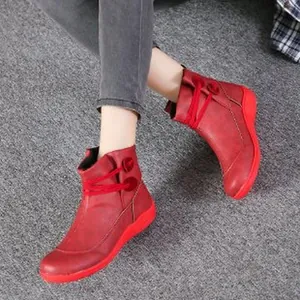Nahaufnahme von roten Retro-Lederstiefeletten mit modischen Schnür- und Knopfdetails.