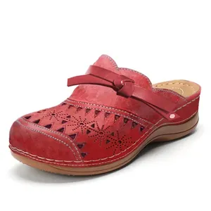 Close-up of red women's wedge clogs featuring hollow-out floral patterns and bow strap