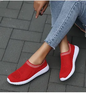 Detailed view of red breathable knit slip-on sneakers for women shown on a model.
