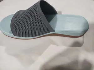 Side view of fly-knit flat slipper with grey mesh strap and blue sole