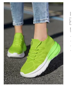 Close-up of lime green flyknit sock sneakers with thick white soles on asphalt.