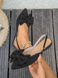Detail van zwarte platte sandalen met puntige neus en een elegante grote strik