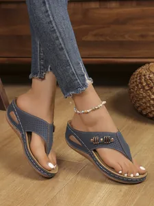 Close-up of women's navy blue wedge thong sandals with perforated design and stitching.