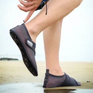 Detailed view of gray breathable mesh water shoes being worn on a natural sandy beach