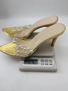 Elegant gold stiletto mule with pearl-encrusted clear strap, weight displayed on scale.