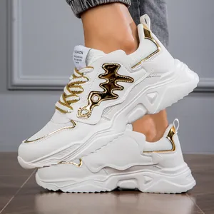 Detail view of men's chunky white sneakers with metallic gold accents and platform sole