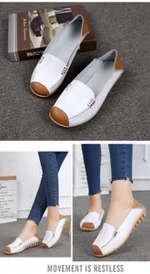 Model wearing white round-toe loafers with brown accents on a textured grey background