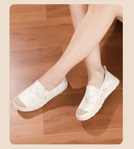 Primer plano de alpargatas de encaje blanco para mujer sobre suelo de madera
