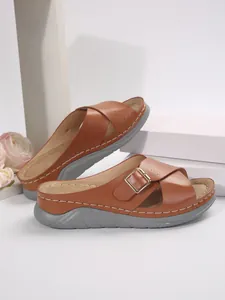 Detail view of brown cross-strap platform sandals with gold buckle and contrast stitching