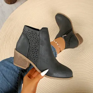 Detailweergave van grijze Chelsea boots met uitsnijdingen, blokhak en rits opzij