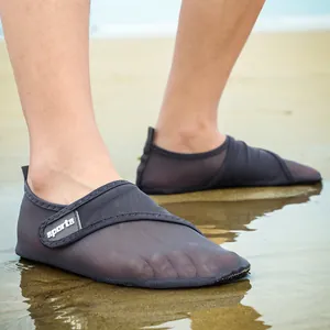 Close-up view of grey breathable mesh water shoes with sports strap worn on a sandy beach