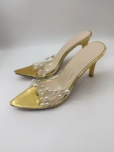 Detail view of gold high heel sandals with pearl-studded transparent straps