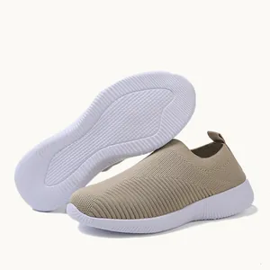 Detail of women's beige flyknit slip-on sneakers with white textured non-slip outsole.