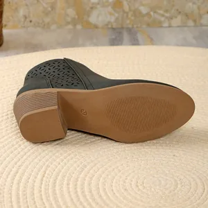 Detail view of the brown sole and laser-cut design on black pointed-toe boots.
