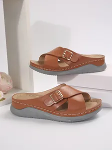 Detailed view of women's brown cross-strap platform sandals with metal buckle design