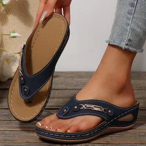 Primer plano de sandalias de cuña azul marino con hebilla dorada y costuras blancas