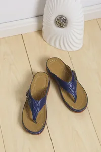 Infradito blu da donna con plantare trapuntato su sfondo di pavimento in legno.