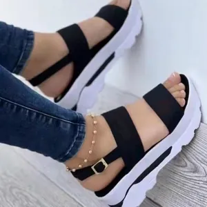 Dettaglio di sandali con zeppa neri alla moda da donna con spesse suole bianche.