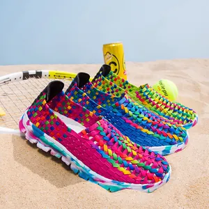 Three pairs of vibrant multi-color woven slip-on shoes for women on a sunny beach