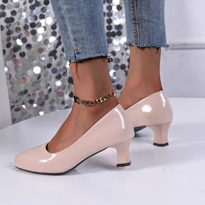Detailed close-up of elegant nude patent leather chunky heel pumps worn by a model