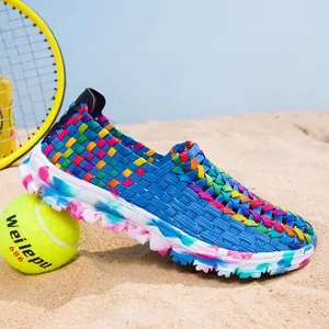 Detailed side view of multicolor woven elastic casual loafer for women on beach sand