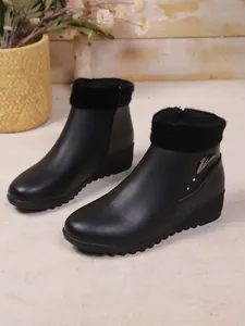 Detailweergave van zwarte sleehak enkellaarsjes met warme nepbontrand en metalen accent.