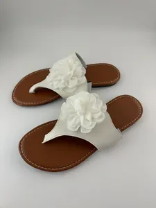 Primer plano detallado de flor de tela blanca en sandalias de dedo planas marrones