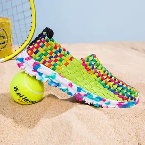 Detailed side view of colorful woven breathable slip-on shoes on a beach setting