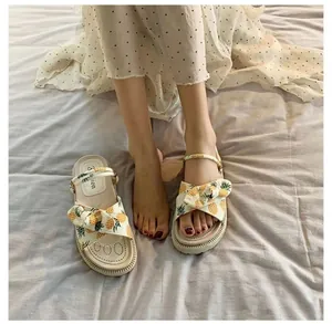 Detailed view of pineapple print platform sandals worn by a model
