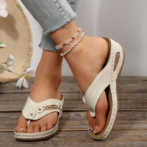 Primer plano de sandalias blancas con cuña y tiras perforadas con hebillas de metal