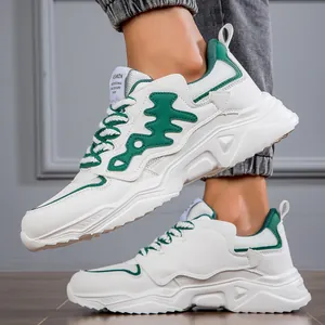Close-up side view of men's chunky white sneakers featuring green accents and thick soles.