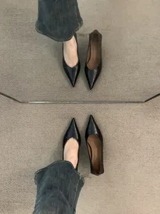 Vista de espejo de elegantes zapatos de tacón negros con punta y textura tejida