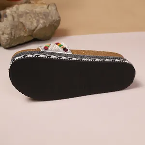 Vista detallada de la suela negra texturizada y la tira con cuentas de las sandalias