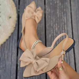 Elegante beige platte sandalen met grote strikdecoratie en spits slingback-ontwerp.