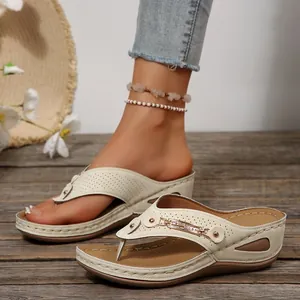 Vista detallada de sandalias beige con cuña, correas perforadas y hebilla decorativa